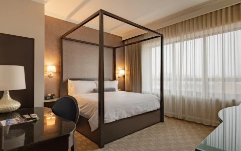 a dim lit room with a canopy bed and desk