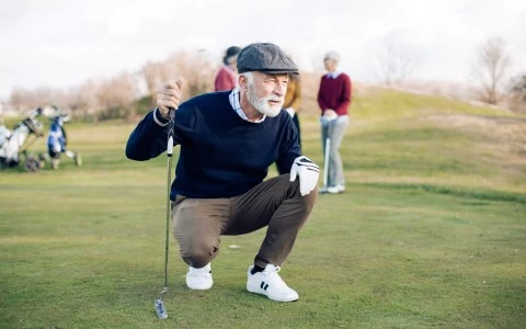 a man kneeling on the golf course looking straight ahead