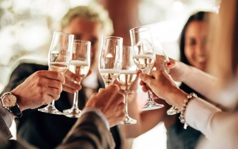 smiling men and women clinking their flutes 