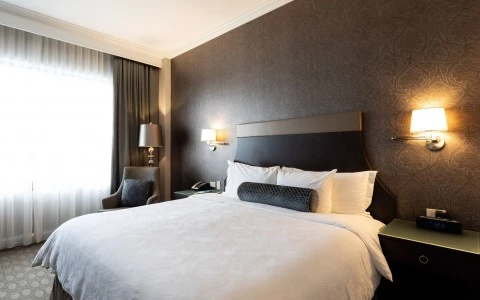 a bed in an elegant room with a purple and gold wallpaper accent wall