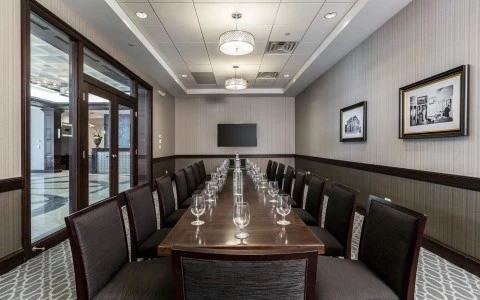 a long wooden table with black chairs in a private dining room