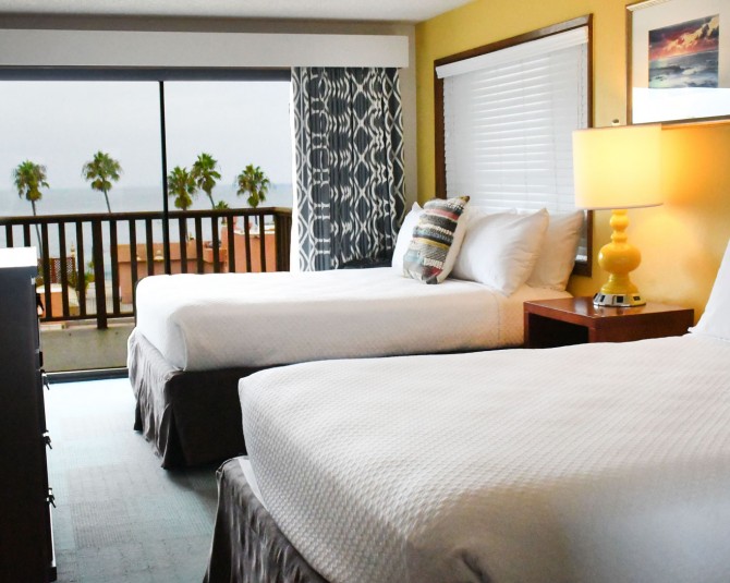 room with 2 beds and a large windows with a view of the water picture 0