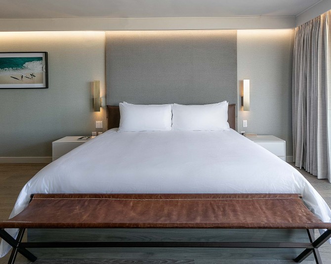 large white bed with brown leather long seat at the foot of the bed picture 2