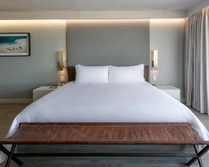 large white bed with brown leather long seat at the foot of the bed picture 2