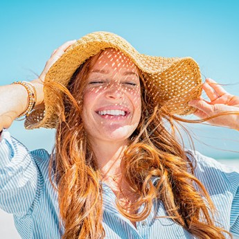 girl in a sunhat soaking up the sun on the beach