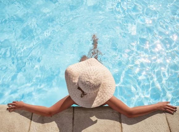 a woman in a hat sitting in a pool