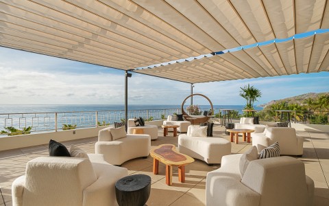 a patio with white furniture and a large white umbrella over it