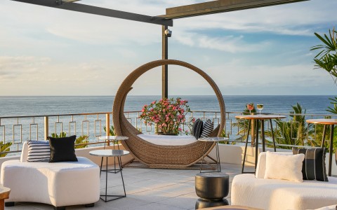 a patio with a large round chair and a table with flowers on it