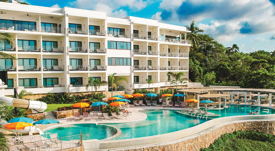 a pool with umbrellas and chairs in front of a building