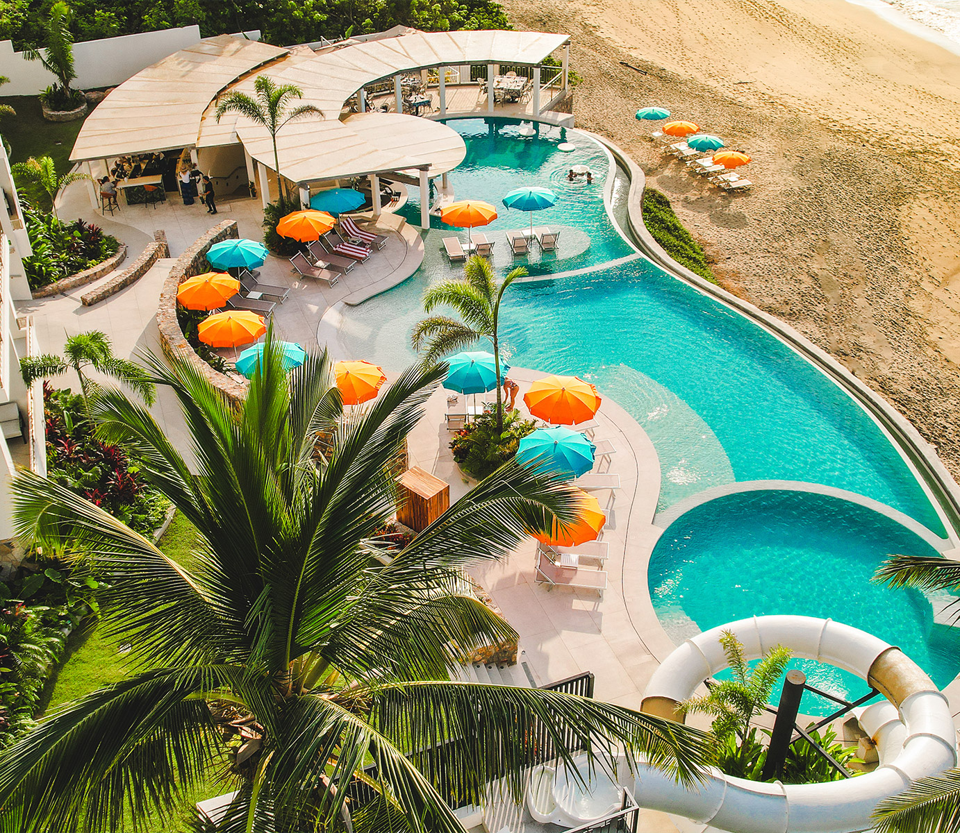 a pool with a beach and palm trees