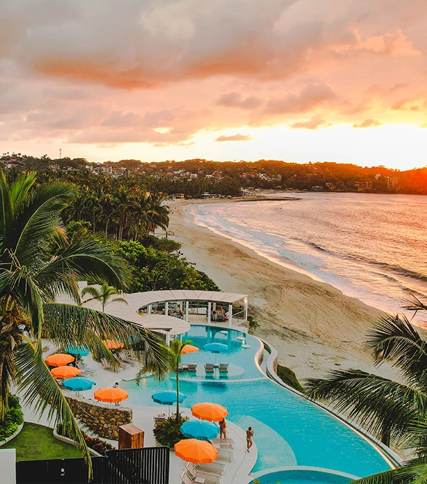 a pool with a beach and umbrellas by it