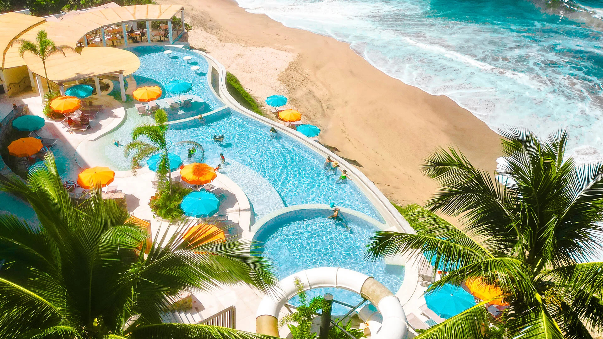 a pool with umbrellas and palm trees on a beach
