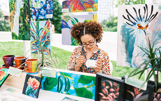 a woman sitting at a table with paintings