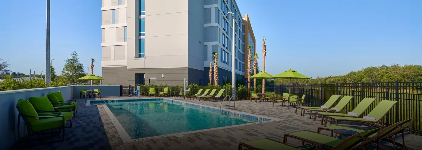 a pool with chairs and umbrellas next to a building