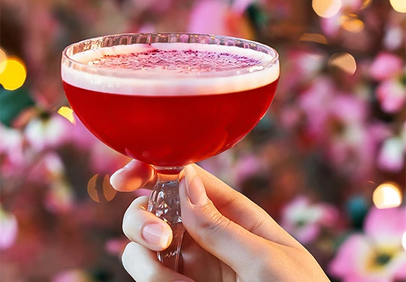 a hand holding a glass of red liquid