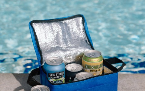 a cooler bag with cans and cans in front of a pool