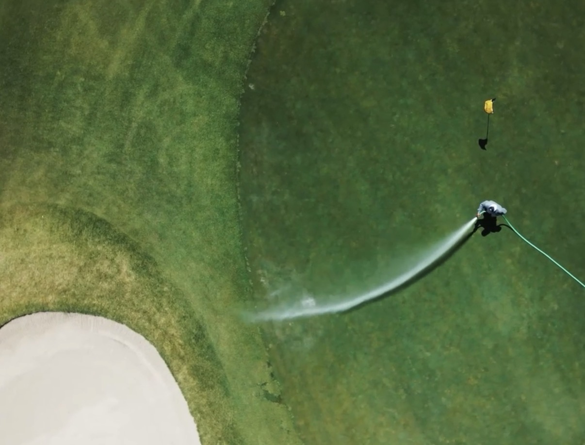 a person spraying water on a golf course