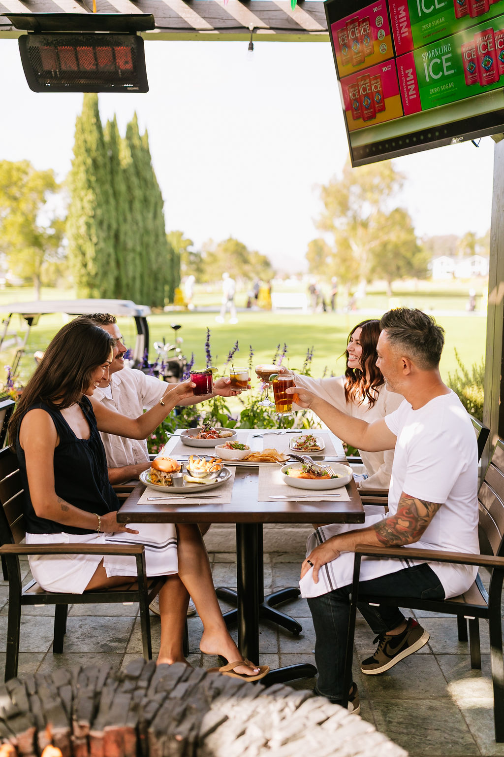 a group of people sitting at a table with food and drinks