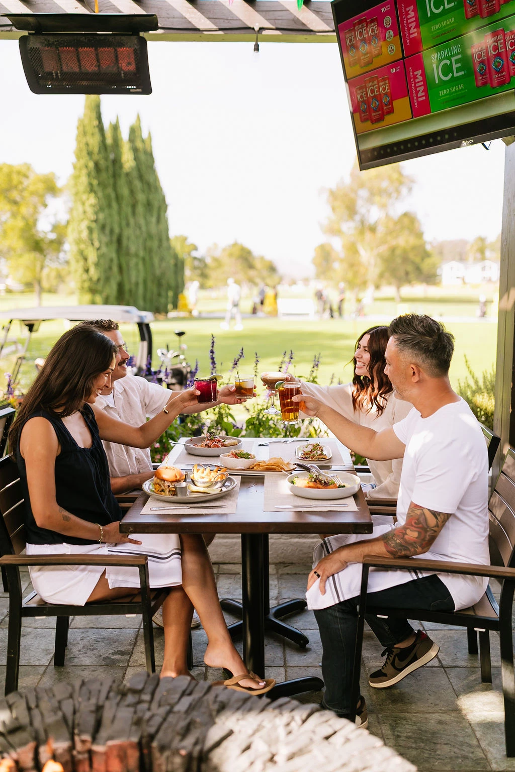 a group of people sitting at a table with food and drinks