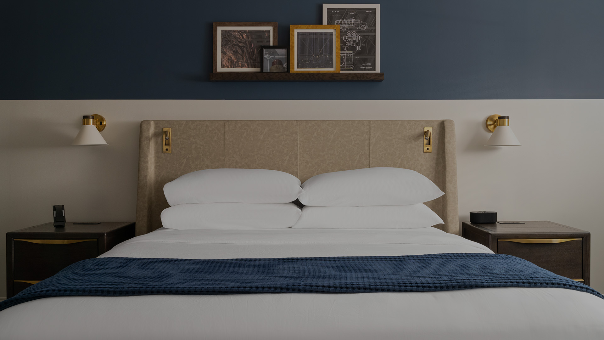a bed with a blue blanket and a lamp on the side
