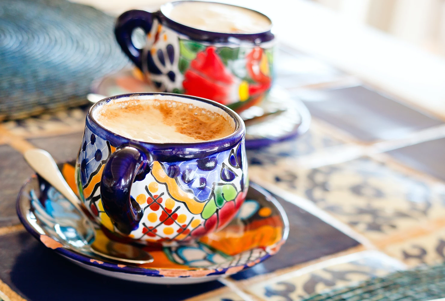 two colorful cups with coffee over a table