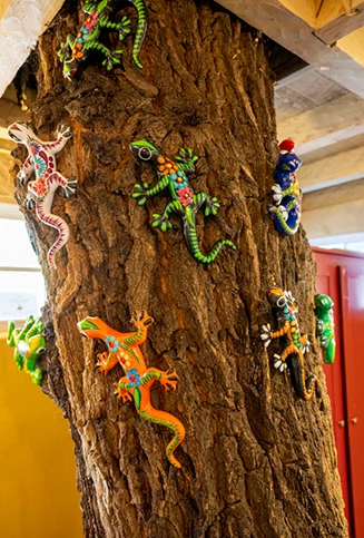 a tree trunk with colorful iguanas decorating
