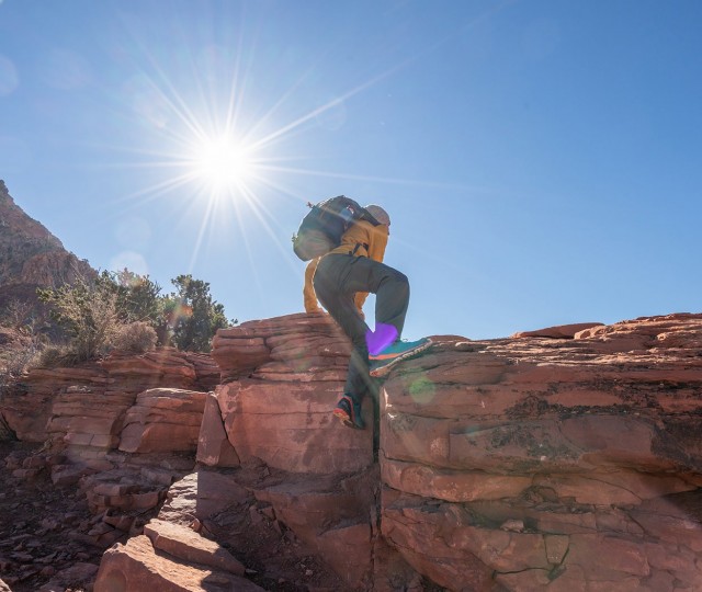 A man hiking a rocky mountain with the sun shining
