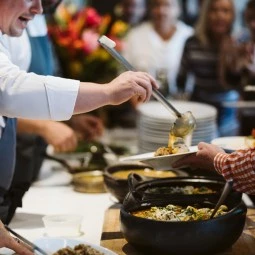 chefs serving food to guests during the cooking demonstration 