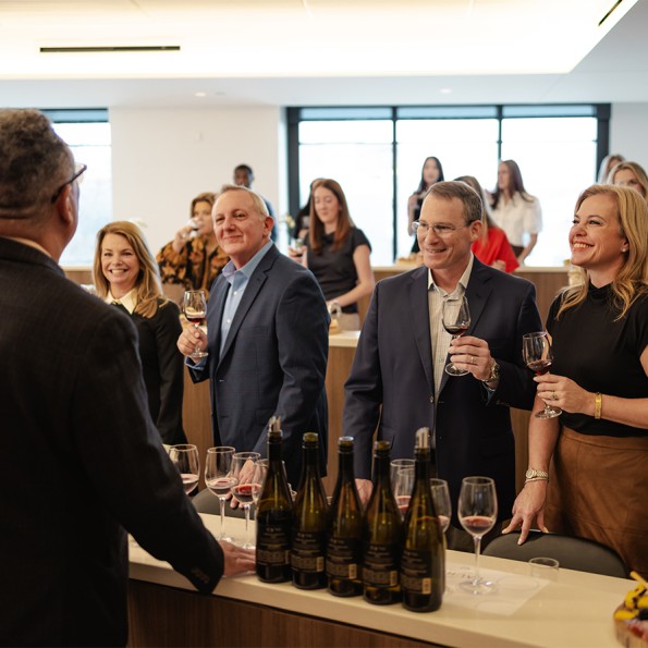 a group of people standing around a bar with wine glasses preview