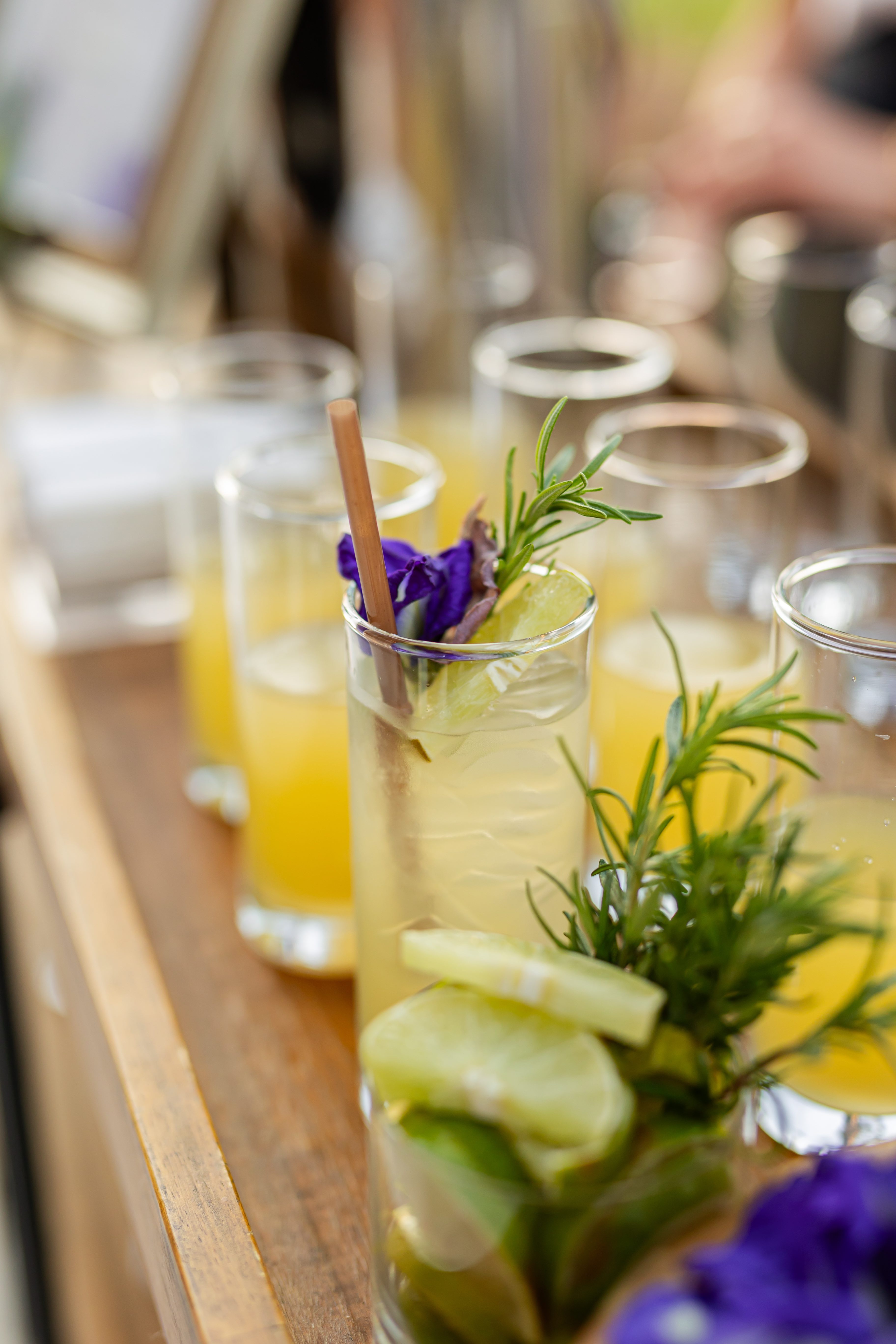 a group of glasses with yellow liquid and a flower in them