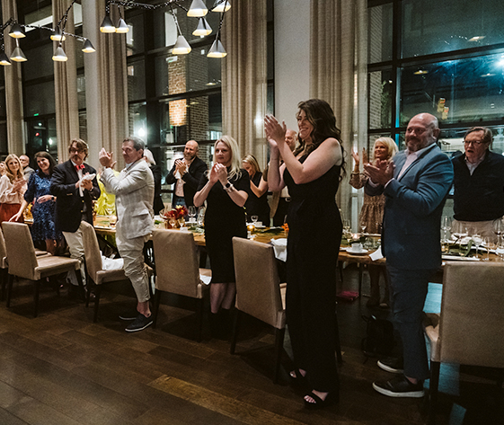 a group of people clapping at a dinner