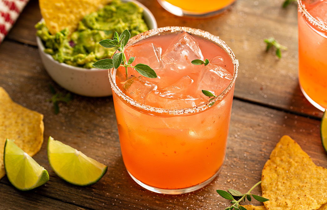 a glass of orange drink with ice and mint leaves