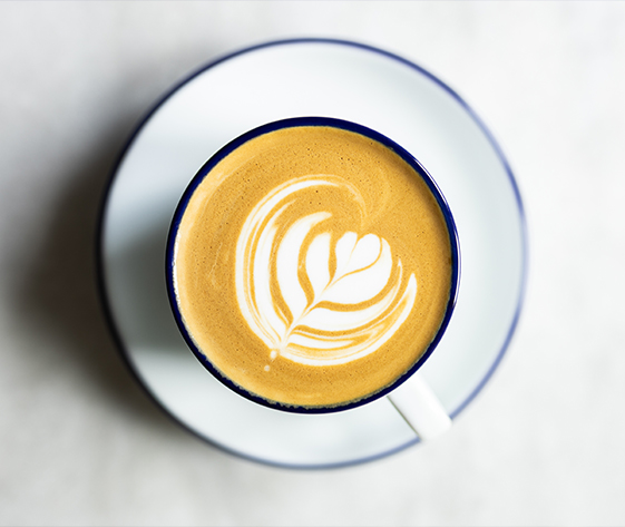 a cup of coffee with a leaf design in the foam