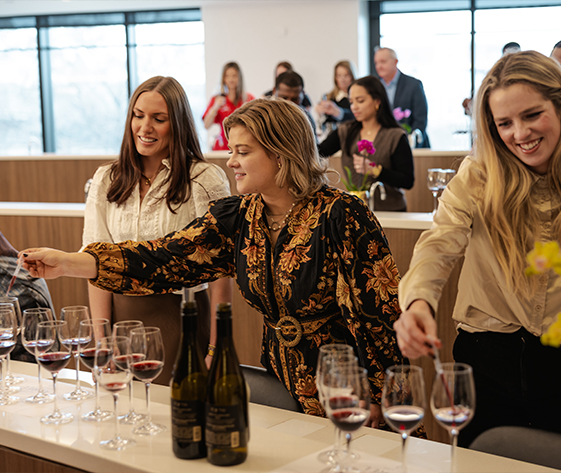 a group of women standing around a table with wine glasses
