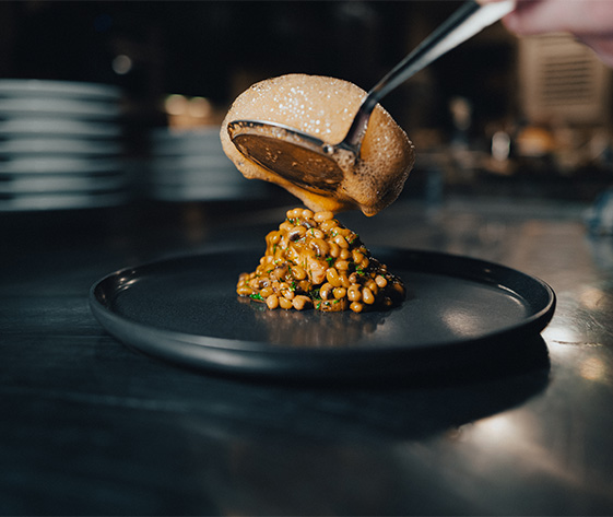 a person pouring sauce onto a plate of food