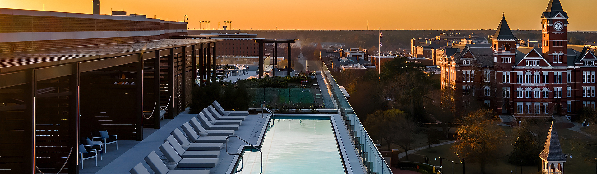 a pool with a railing and a rooftop with a city in the background