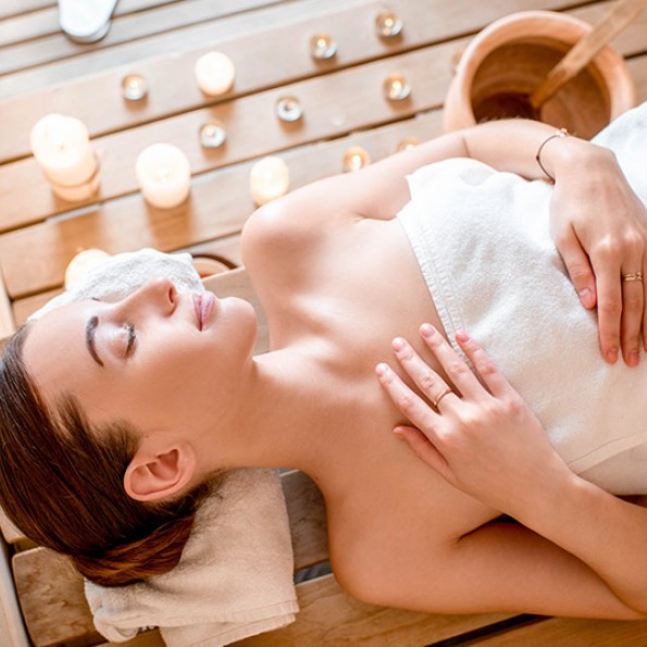 overhead view of a woman wrapped in a towel laying in a sauna preview