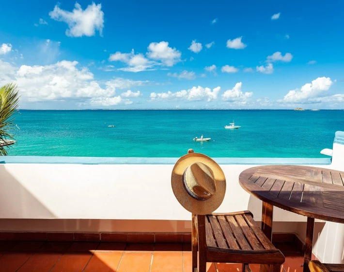 a deck with chairs and a table overlooking a body of water