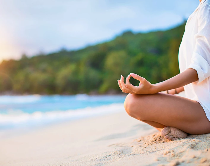 A woman meditating overlooking the ocean.