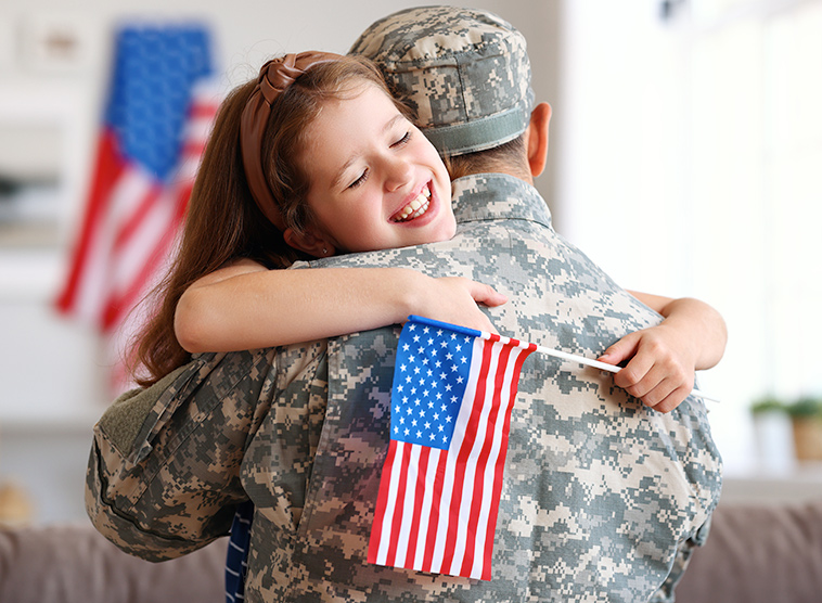 little girl hugging a militar