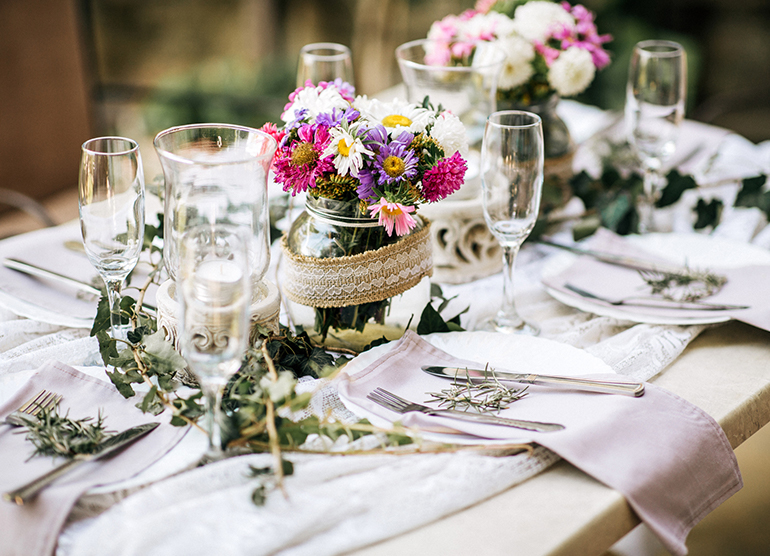 table decorated with flowers and greens for a wedding
