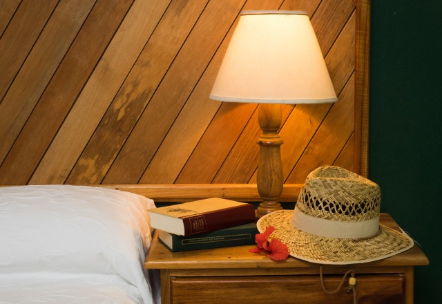guest room night styled with books and a hat next to bed with crisp white linens