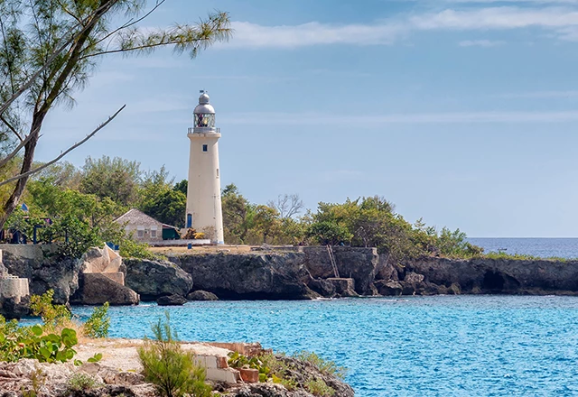 regal white lighthouse on cliff overlooking calm ocean waters