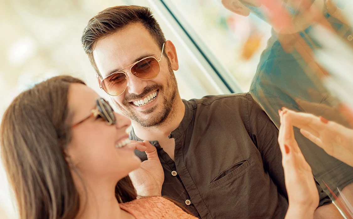 a couple wearing sunglasses smiling at each other