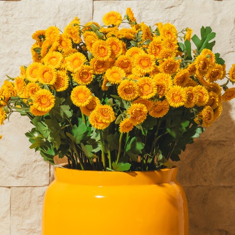a yellow vase with yellow flowers