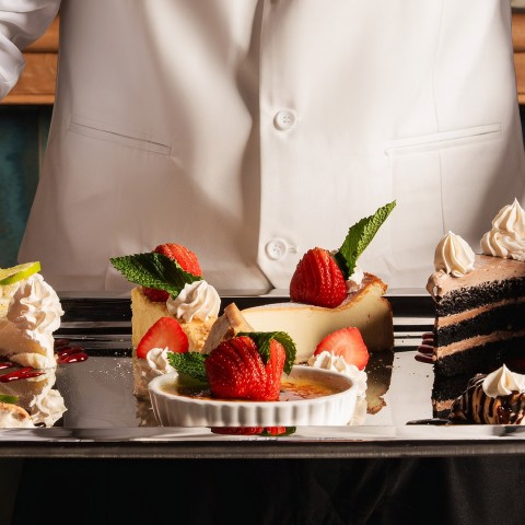 a person holding a tray of desserts