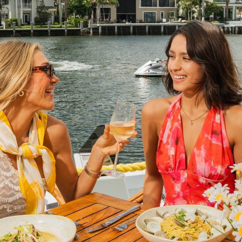 two women sitting at a table with food and drinks on a boat