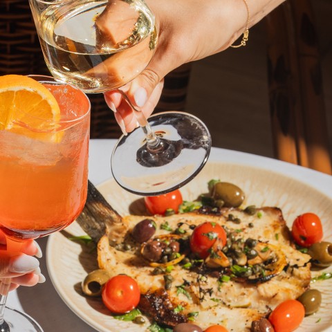 a person pouring wine into a plate of food