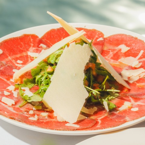 a plate of meat with cheese and greens