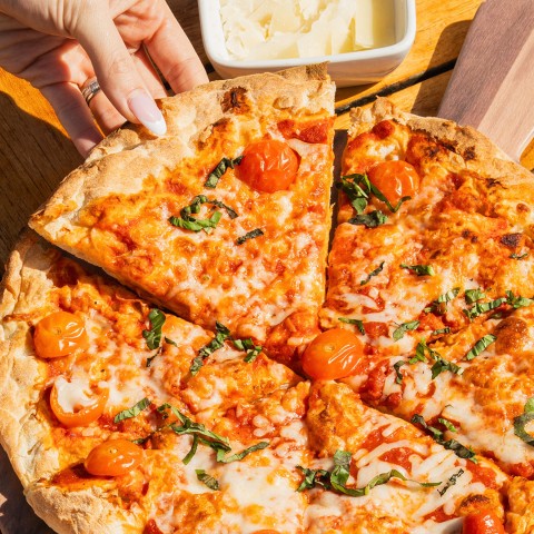 a hand picking up a slice of pizza